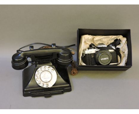 A black bakelite telephone, with pull out drawer, and a Minolta X-500 SLR camera