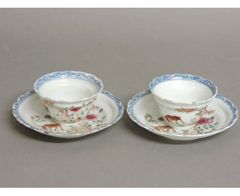 A pair of 18th century Chinese famille rose tea bowls and saucers, each decorated with a deer, a bamboo bush and flowers