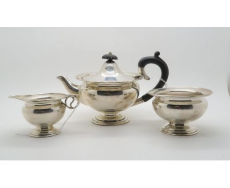 An Edwardian bachelors silver tea service, comprising teapot, sugar bowl and cream jug, the teapot with scrolling wooden hand