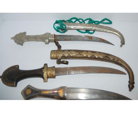 Three middle-eastern daggers in decorative scabbards, tribal dagger in leather scabbard and powder flask, 40cm and smaller Co