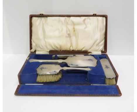 A cased George V silver four piece dressing set, in the art deco style, with engine turned decoration and copper flecked blue