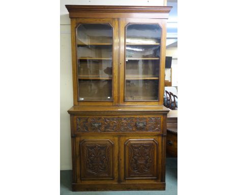 A Victorian oak secretaire bookcase with glazed two door bookcase above single drawer secretaire base with two carved panel d