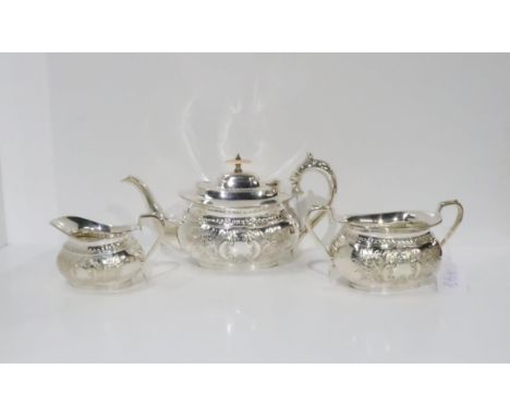 A three piece EPNS tea service, comprising tea pot, milk jug and sugar bowl, of shaped form with repousse scrolling foliage d