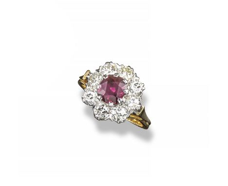 A ruby and diamond cluster ring, the oval-shaped ruby is set within a surround of eight round brilliant-cut diamonds in plati