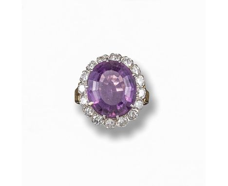 An amethyst and diamond ring, the oval-shaped amethyst is set within a surround of circular-cut diamonds in platinum and gold