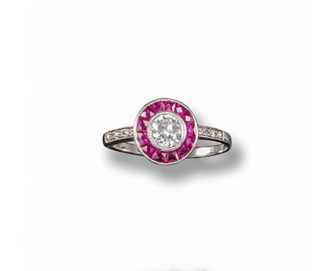 A ruby and diamond target ring, the circular-cut diamond is sent within a surround of French-cut rubies within further diamon
