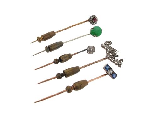 A gold stick pin mounted with a pear-shaped jade cabochon, a gold stick pin set with two sapphires and a diamond, a gold stic