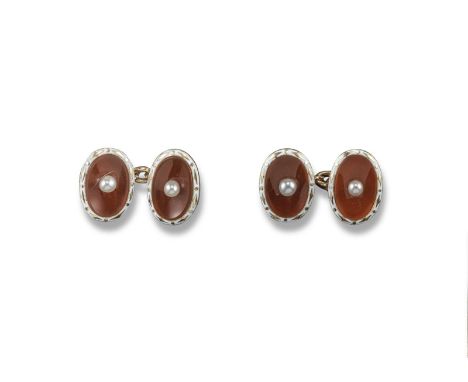 A pair of carnelian cufflinks, the concave oval carnelian sections are each centred with a seed pearl and set in gold with wh