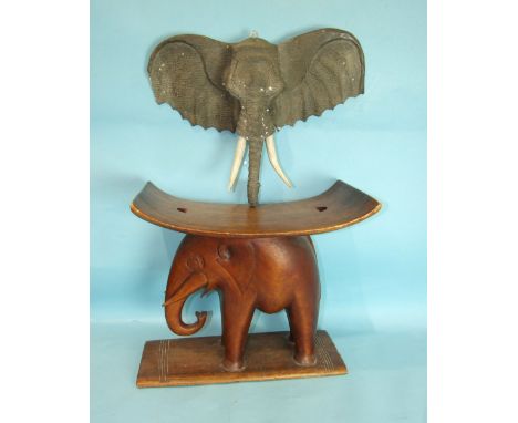 A carved wood stool in the form of an elephant, 46cm high and a carved wood wall-mounted elephant's mask, 45 x 53cm, (2). 