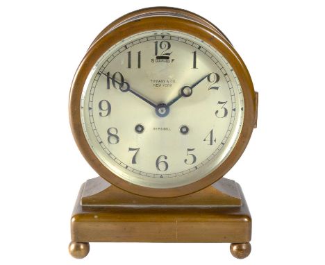 A Tiffany & Co Ship's Bell clock In brass case with silvered 14cm dial on ball feet. Serial no.96937Please see the multiple i