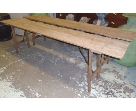 FOLDING TABLES, a pair, early 20th century pine with folding and locking action iron bracket trestle supports, 45cm D x 241cm