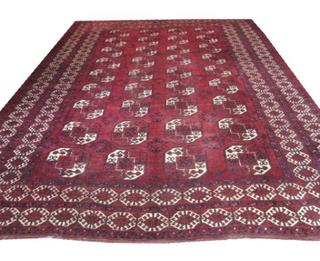 ANTIQUE AFGHAN CARPET, 435cm x 338cm, repeat tribal guls and hooked medallions on a ruby field within multiple borders. 