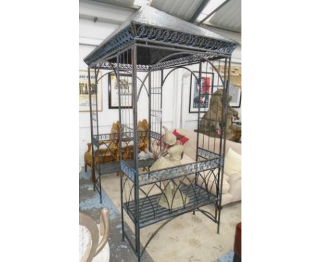 GAZEBO, of pitched roof over iron bench and end supports of arches and fleur de lys decoration, 265cm H x 190cm L x 115cm W. 
