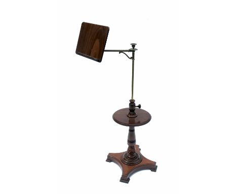 An Edwardian mahogany adjustable reading stand, with brass arm, circular shelf on a turned column with platform base, maximum
