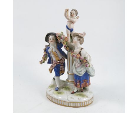 A Continental porcelain figure group, of a cherub standing on a plinth with a couple beneath holding a flower garland, on ova