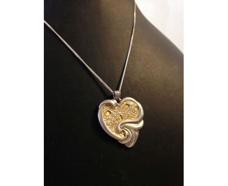 A silver heart shaped 'footsteps' pendant with gold highlights, on a silver chain.