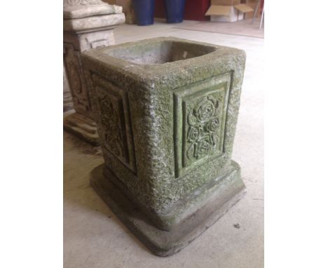 A square concrete garden planter with flower decoration, approx 45cm tall and 32cm square.