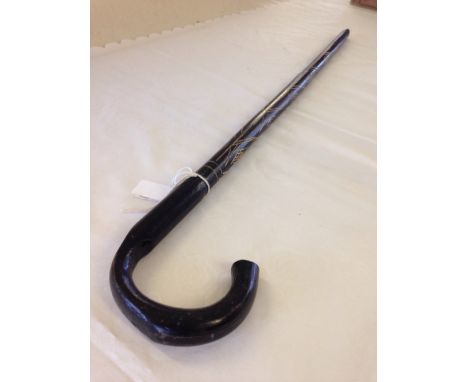 A carved black painted bamboo walking stick.