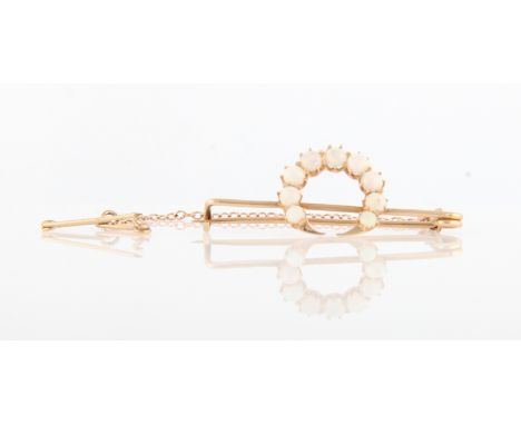 An opal crescent design brooch, set with nine graduated circular opal cabochons, in unmarked yellow metal, length approx. 3.5