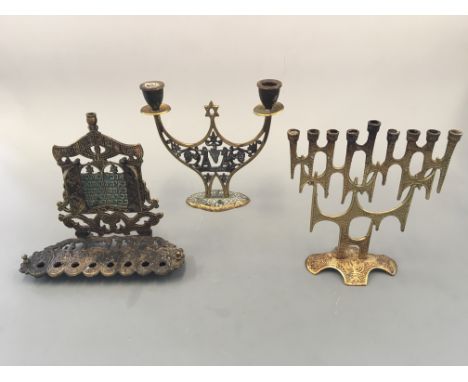 Two brass nine-lamp menorahs with a two-lamp candlestick holder with Star of David. Heights approximately 21cm.