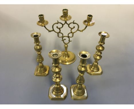 Two pairs of brass candlestick holders with one three branch candlestick holder.