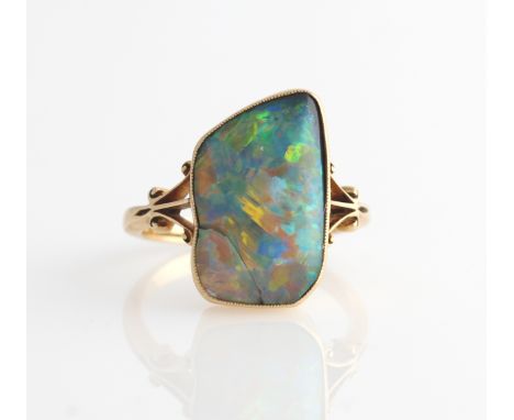 An 18ct yellow old opal ring set with an irregular piece of opal, measures approx. 10x17mm, with open metal work scroll desig