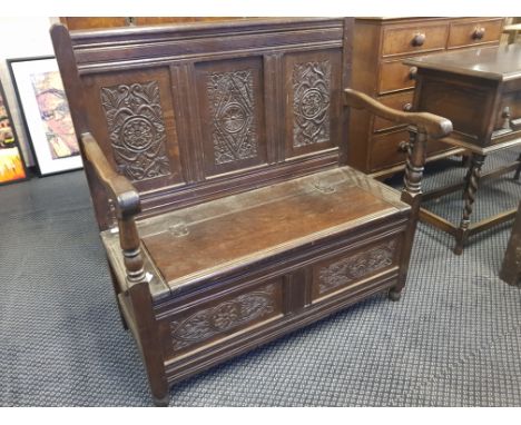 A carved oak hall bench with storage seat.