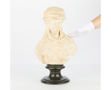 Alabaster carved bust on a stone plinth in the form of a figure with a head covering and cloak.Height: 20 1/2 in x width: 12 