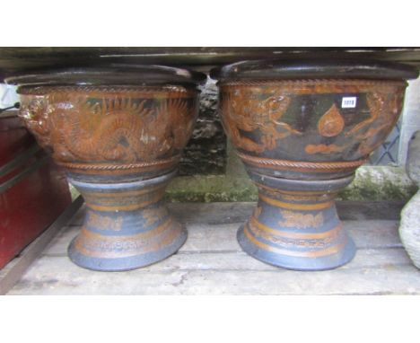 A pair of Chinese brown treacle and honey coloured glazed jardinieres on waisted stands with raised trailing dragon, pearl an