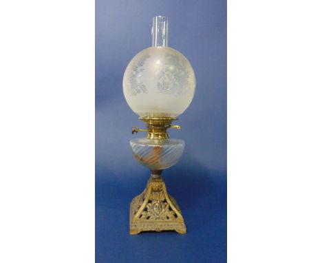 A Victorian oil lamp with pierced and cast iron base, wide fluted font and etched glass globe