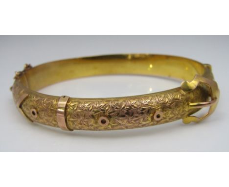 An attractive 9ct hinged bangle in the form of a buckled belt engraved with foliate decoration, inner dimensions 6.1 x 5.3cm 