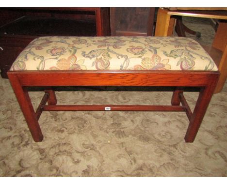 A reproduction Georgian style oak stool of rectangular form with drop in floral tapestry patterned upholstered seat raised on