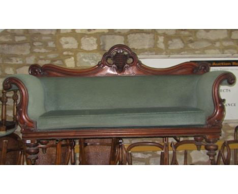 A Victorian double scroll arm three seat sofa, the mahogany showwood frame with scrolling acanthus, fruiting vine and further