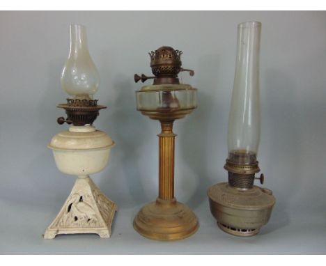 A late 19th century brass column oil lamp with clear glass font and two further examples, one with painted finish