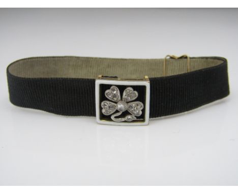 A shamrock motif slider set with rose cut diamonds and white enamel border, on a moire ribbon bracelet with 15ct fastener