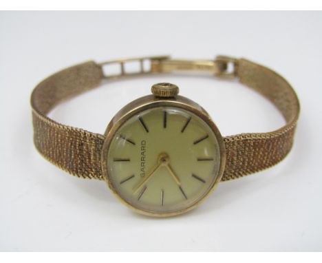 A mid 20th century Garrard ladies 9ct cocktail watch with circular champagne dial fitted with baton markers upon an original 