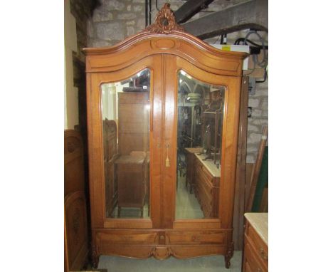 A medium to light oak armoire, the arched cornice with raised carved C scroll and acanthus detail over a pair of three quarte