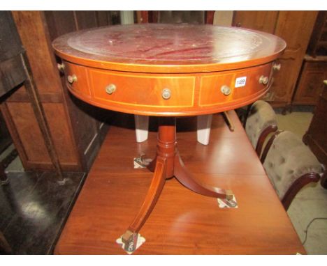 A reproduction Georgian style mahogany drum table, with inset burgundy leather panelled top, over a frieze of real and dummy 