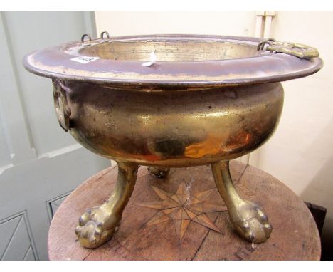A 19th century or earlier brass brazier, of circular form raised on three stout claw and ball supports, with brass axe head h