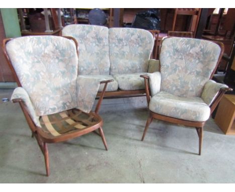 An Ercol stained beechwood three piece Windsor style suite comprising two seat sofa and a pair of matching armchairs with sti