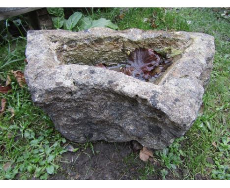 A small weathered rough hewn garden trough with shaped outline