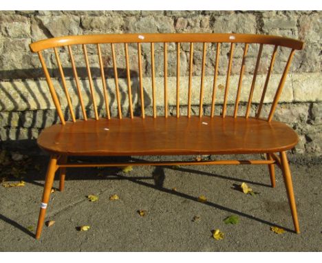 A vintage Ercol light elm and beechwood love seat with stickback and splayed supports united by a central high stretcher