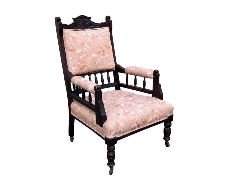 An Edwardian carved and stained walnut open armchair the square, padded spindle back with shaped foliate carved crest rail, o
