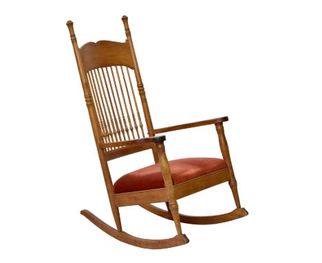 An Art Nouveau style beechwood rocking chair, early 20th century, the spindle back with deep, cornucopia carved top rail, ove