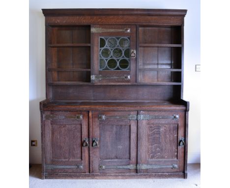 An Arts &amp; Crafts oak dresser, probably by Liberty &amp; Co. c.1900, the moulded cornice over a back with central leaded, 