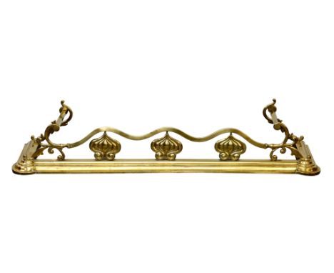 An Art Nouveau brass fender, early 20th century, with wavy front rail raised on stylised foliate supports, on an ogee plinth 