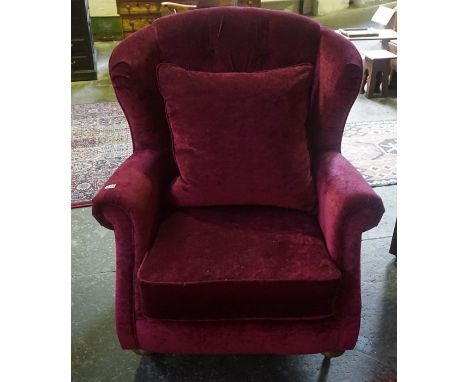 A Chesterfield Style Button Back Wing Armchair, Upholstered in red velour, raised on turned feet with castors, 101cm high 