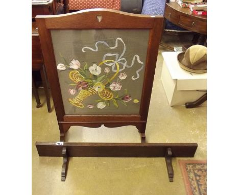 An oak framed floral painted firescreen and an oak plate rack