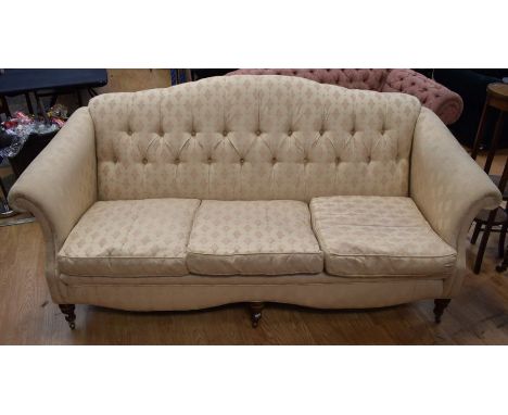 A Victorian button-back three seater settee, shaped back, scroll arms turned legs, brass casters