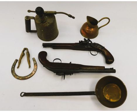 A metal ware collection including a blow lamp, wall hanging pistols, nut crackers, cast cookbook stand